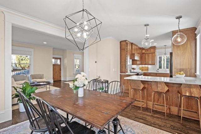 dining space with baseboards, dark wood-type flooring, crown molding, a chandelier, and recessed lighting