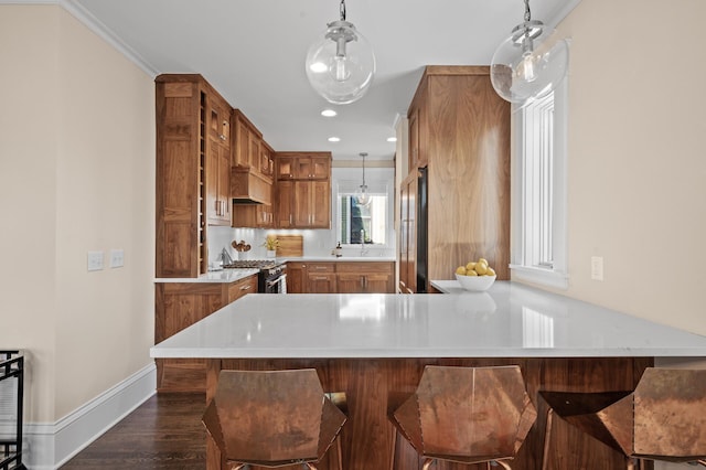 kitchen with high end appliances, a peninsula, brown cabinets, and light countertops