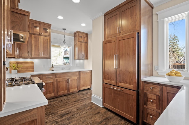 kitchen with dark wood-style flooring, brown cabinets, light countertops, paneled built in fridge, and glass insert cabinets