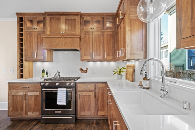 kitchen featuring gas range, light countertops, a sink, and brown cabinetry