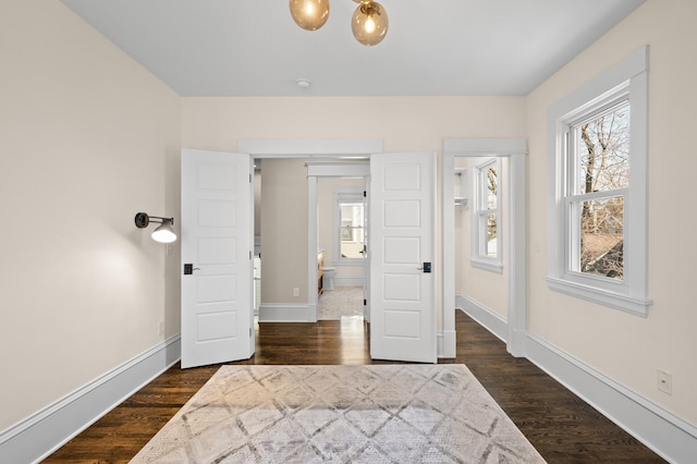 bedroom featuring dark wood-type flooring, multiple windows, and baseboards