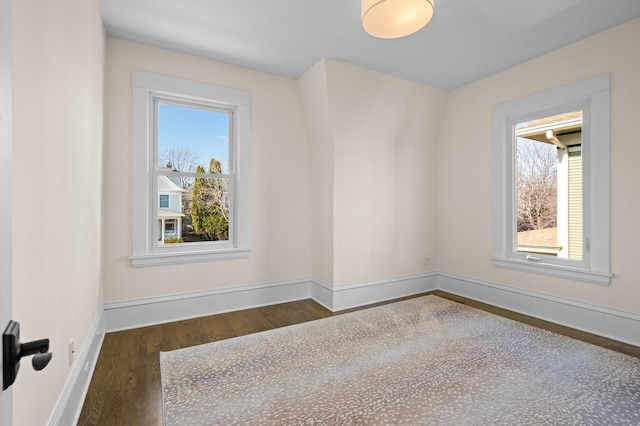 empty room featuring baseboards, wood finished floors, and a healthy amount of sunlight