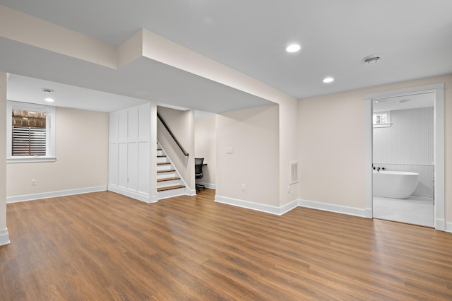 below grade area featuring baseboards, visible vents, wood finished floors, stairs, and recessed lighting