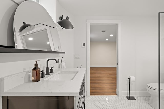 bathroom featuring toilet, tile patterned flooring, baseboards, and vanity