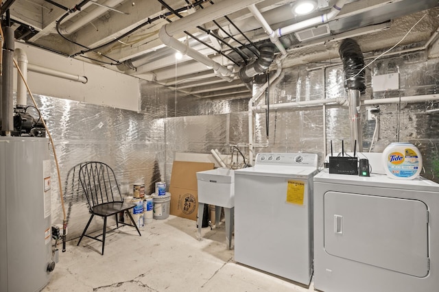 washroom with laundry area, water heater, visible vents, and washing machine and clothes dryer