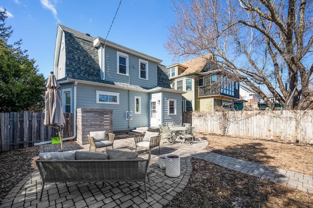 rear view of house with a fenced backyard, outdoor lounge area, a gambrel roof, roof with shingles, and a patio area