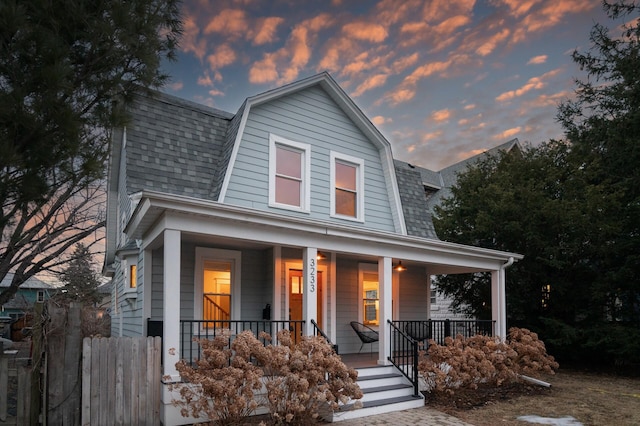 dutch colonial with a shingled roof, a porch, and a gambrel roof