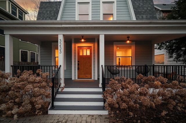 property entrance featuring a porch, roof with shingles, and a gambrel roof