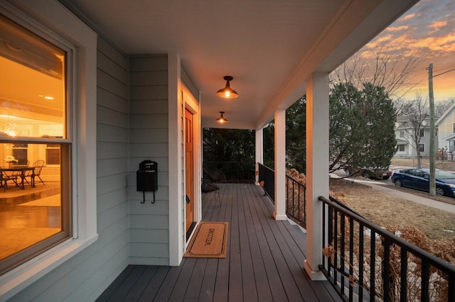 deck at dusk featuring a porch