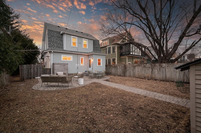 rear view of property with roof with shingles, a patio, a fenced backyard, and a gambrel roof