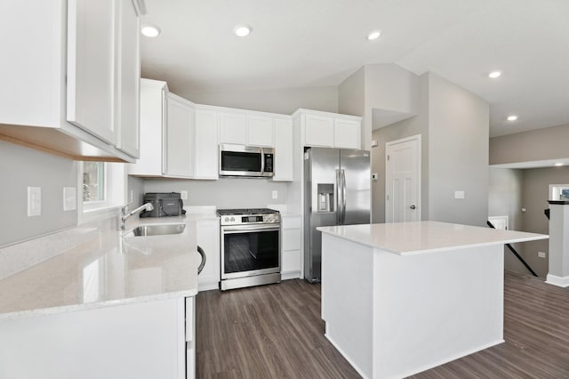 kitchen with a kitchen island, white cabinetry, vaulted ceiling, appliances with stainless steel finishes, and dark wood-style floors