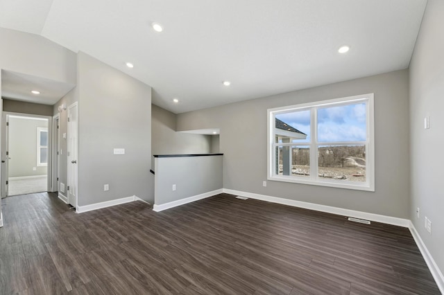 empty room with visible vents, baseboards, lofted ceiling, dark wood-type flooring, and recessed lighting