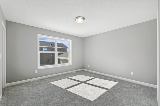 spare room featuring carpet flooring, a textured ceiling, and baseboards