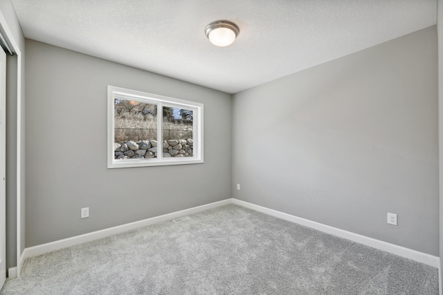 carpeted empty room with baseboards and a textured ceiling