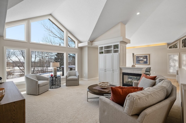 carpeted living room with a healthy amount of sunlight, high vaulted ceiling, a fireplace, and baseboards