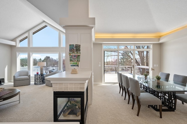 dining space with vaulted ceiling, a tile fireplace, and light colored carpet