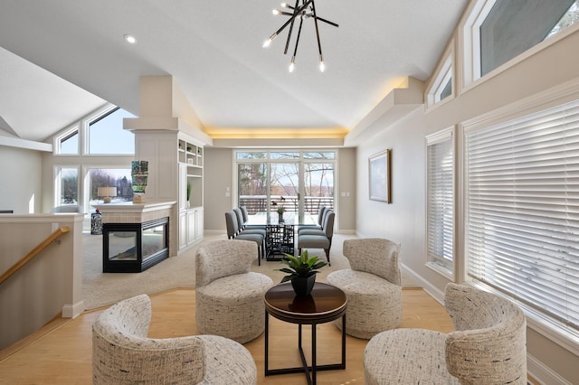 sitting room featuring baseboards, a tiled fireplace, lofted ceiling, an upstairs landing, and a notable chandelier