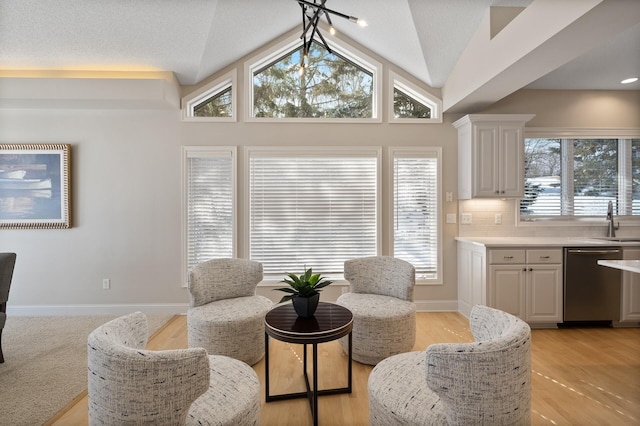 sitting room with lofted ceiling, a textured ceiling, and baseboards