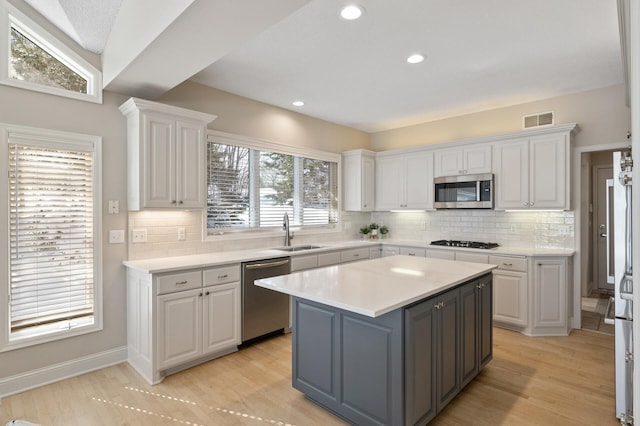 kitchen with a sink, visible vents, white cabinetry, light countertops, and appliances with stainless steel finishes