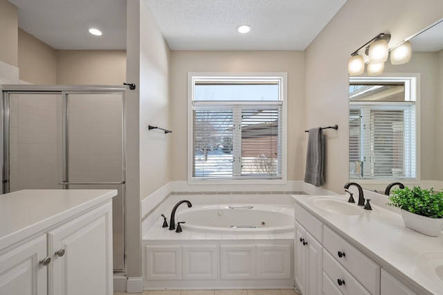 bathroom with double vanity, a sink, a textured ceiling, a shower stall, and a whirlpool tub