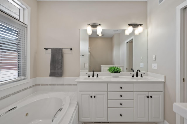 bathroom featuring double vanity, a jetted tub, and a sink