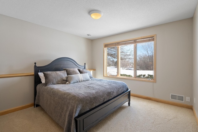 bedroom featuring visible vents, light carpet, a textured ceiling, and baseboards