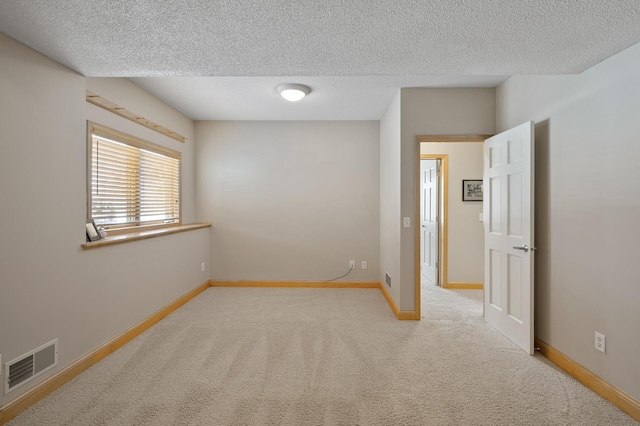 carpeted empty room with visible vents, a textured ceiling, and baseboards