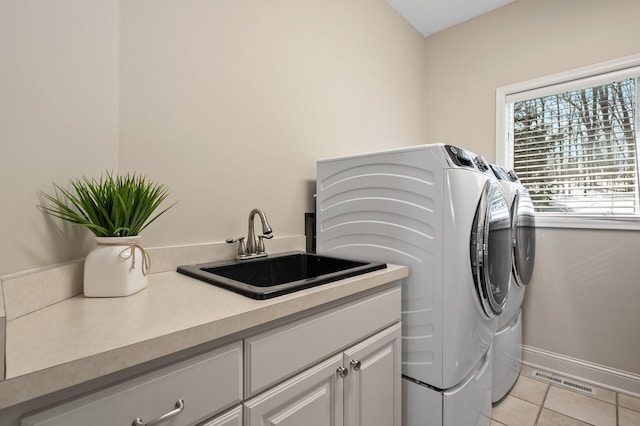 laundry area featuring cabinet space, light tile patterned floors, visible vents, separate washer and dryer, and a sink