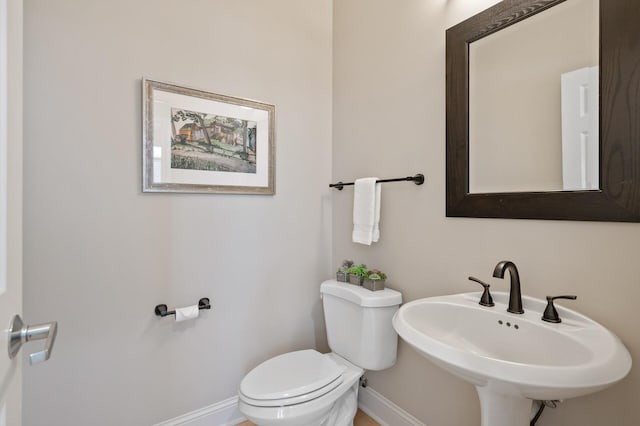 half bath with a sink, toilet, and baseboards