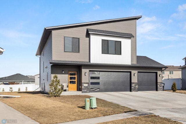 view of front of house with stone siding, an attached garage, driveway, and fence