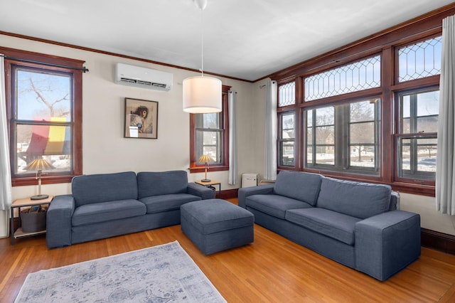 living room featuring baseboards, ornamental molding, wood finished floors, and a wall mounted AC