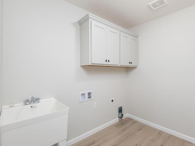 laundry area with cabinet space, visible vents, light wood-style floors, washer hookup, and a sink