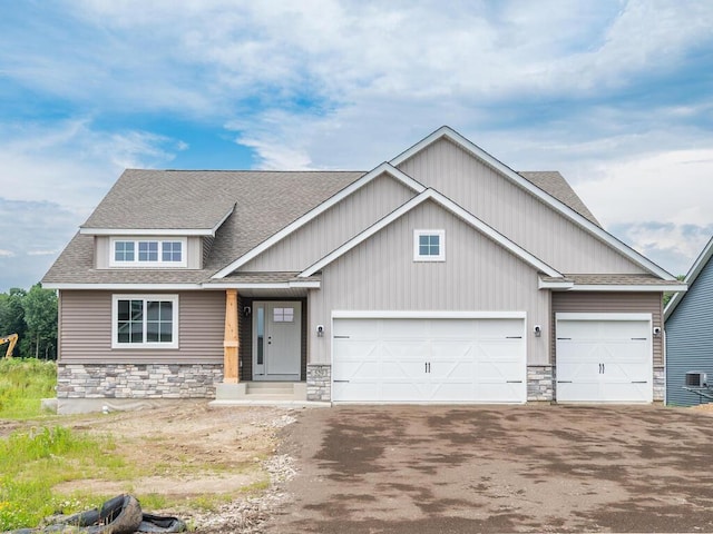 craftsman-style house featuring a garage, stone siding, a shingled roof, and aphalt driveway