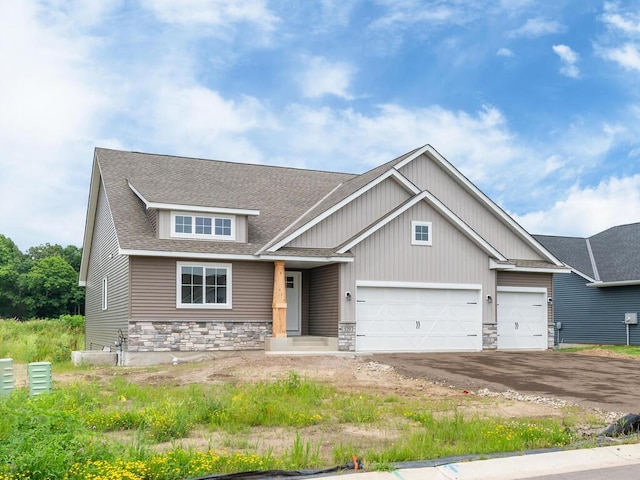 craftsman house featuring a garage, stone siding, roof with shingles, and driveway