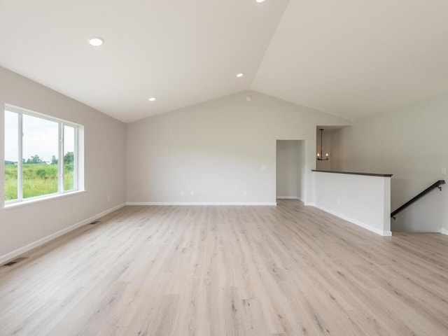 unfurnished living room with lofted ceiling, light wood finished floors, visible vents, and baseboards