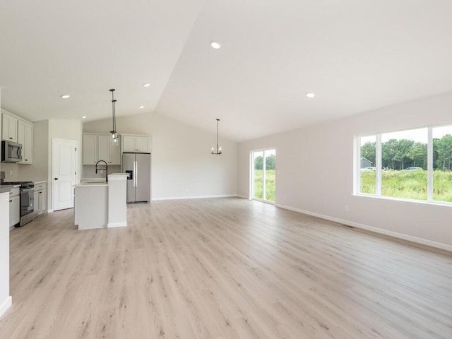 unfurnished living room with light wood finished floors, baseboards, vaulted ceiling, and a sink