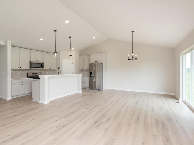 kitchen with stainless steel appliances, light countertops, open floor plan, a sink, and a chandelier