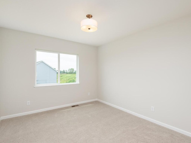 spare room featuring light carpet, visible vents, and baseboards