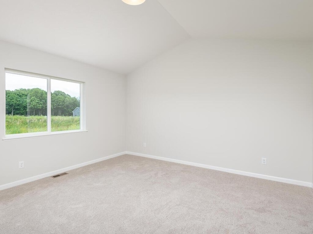 spare room with vaulted ceiling, carpet flooring, visible vents, and baseboards