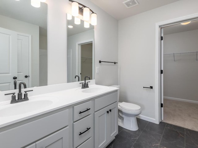 bathroom featuring toilet, double vanity, visible vents, and a sink