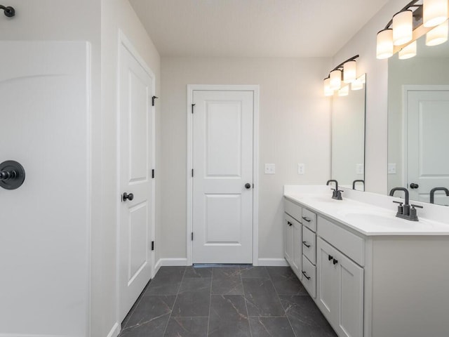 full bath featuring marble finish floor, a sink, baseboards, and double vanity