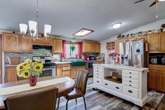 kitchen featuring ventilation hood, backsplash, a sink, crown molding, and appliances with stainless steel finishes