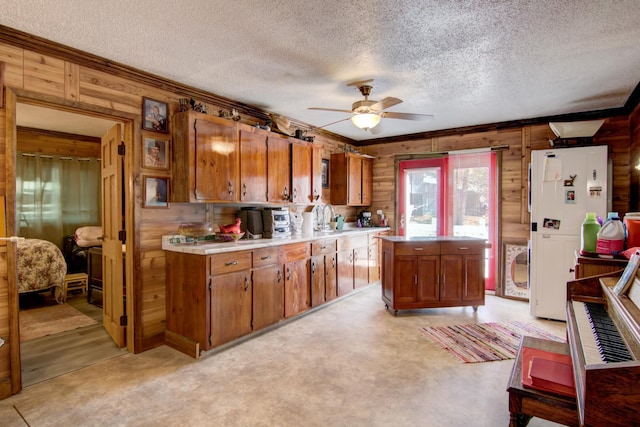 kitchen with ceiling fan, crown molding, a textured ceiling, and wooden walls