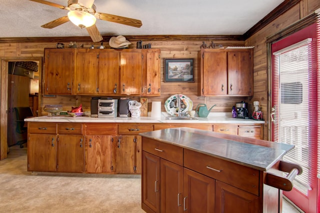 kitchen featuring brown cabinetry, light countertops, wood walls, and a healthy amount of sunlight