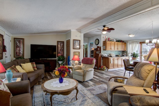 living room with light wood-style flooring, a textured ceiling, crown molding, and a ceiling fan