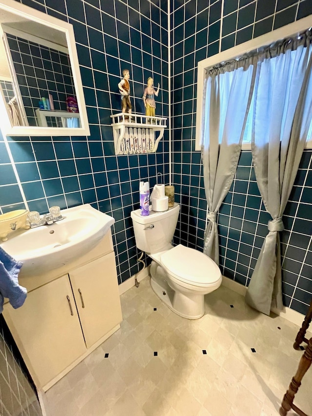 half bathroom with tile walls, vanity, and toilet