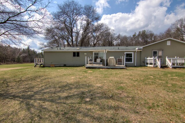 back of property featuring a wooden deck, a lawn, and crawl space