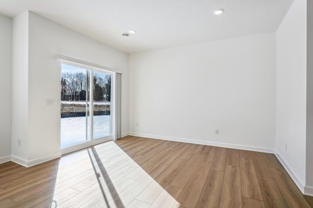 spare room featuring recessed lighting, wood finished floors, and baseboards