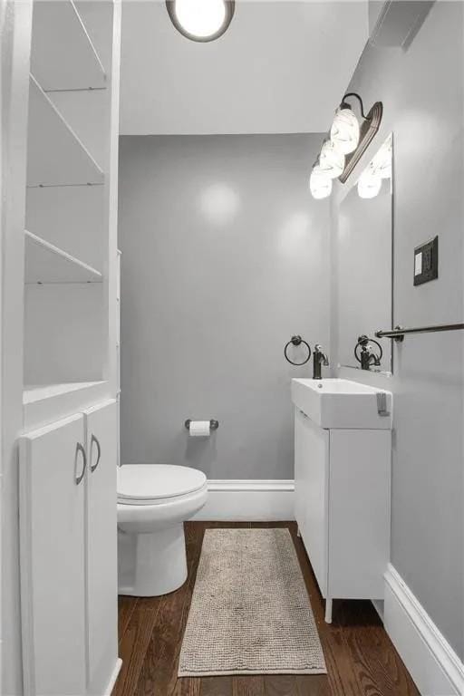 bathroom with baseboards, vanity, toilet, and wood finished floors