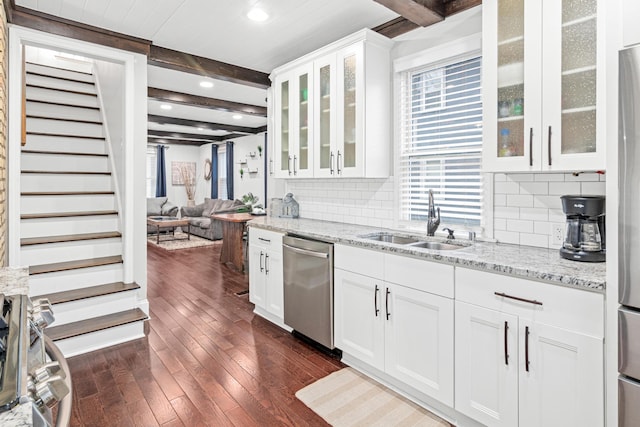 kitchen with a sink, appliances with stainless steel finishes, decorative backsplash, dark wood-style floors, and beamed ceiling